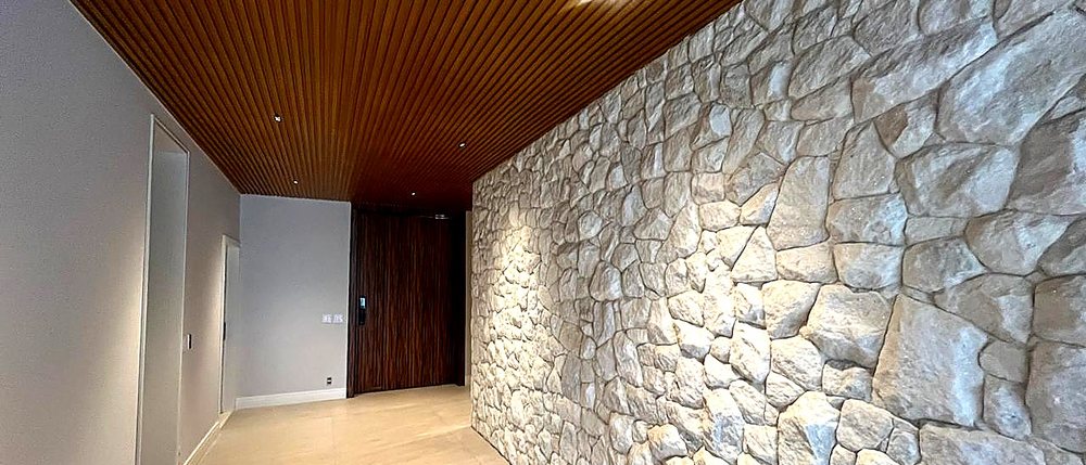 Residência de alto padrão em São Paulo, em execução. Corredor principal em pedra moledo com forro ripado em madeira.